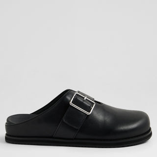 Black mules with a silver buckle on a light gray background
