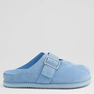 Blue slip on mule with a buckle on a light gray background