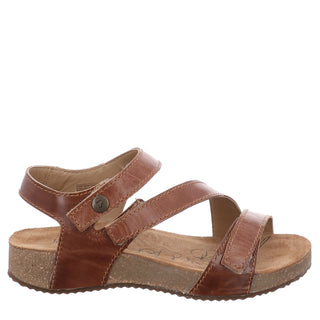 A brown leather sandal with a cork-effect sole and adjustable velcro straps, featuring a modern low wedge heel.